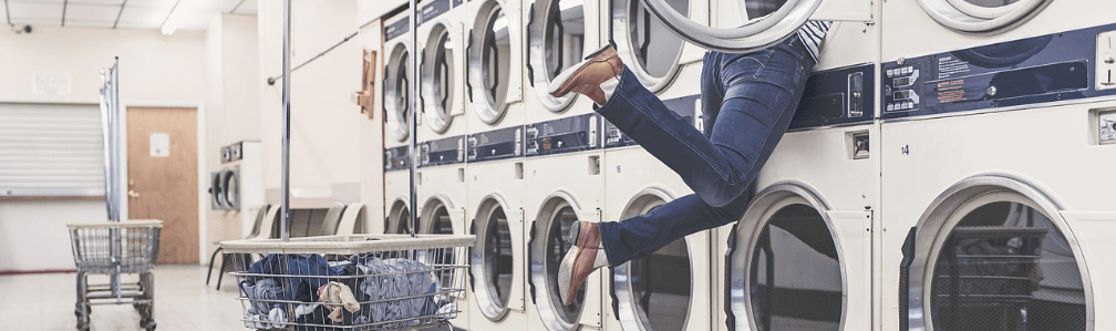 legs dangling out of washing machine at laundromat